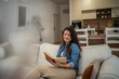© Migma_Agency - Woman relaxing at home, enjoying reading book on sofa