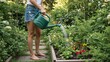 © Vasiliy - Woman watering plants in a lush garden with a green can. Barefoot female gardener caring for flowers in a raised bed in the backyard. Summer gardening hobby concept