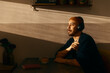 © Francis - A peaceful man wearing headphones sits at a kitchen table, enjoying music or a podcast in the warm glow of sunset. The golden hour light creates a serene atmosphere in a cozy home environment.