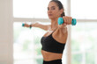© Prostock-studio - Domestic Training With Weights. Fit woman doing exercises with dumbbells, strengthening her body and arms at home or fitness studio, selective focus on equipment. Female working on her biceps muscles