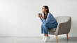 © Prostock-studio - Time for coffee. Charming millennial woman sitting in armchair, enjoying cup of hot drink against white studio wall, banner with free space. Young lady relaxing with mug of warm beverage