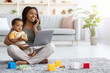 © Prostock-studio - Remote Work With Baby. Happy Black Mom Using Laptop And Talking On Cellphone While Taking Care Of Her Toddler Son At Home, African American Woman Enjoying Distance Job Opportunities, Copy Space