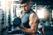 © BuyoutReese05/peopleimages.com - Man, fitness and weightlifting with dumbbell for workout or strength training in gym. Active, male person or lifting weight with bicep curl for strong power, muscle gain or exercise in health club