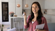 © fizkes - Portrait of cheerful woman stands in modern kitchen, smiling while holding keys and digital tablet, symbolizing new home ownership, real estate purchase, success, independence and property investment