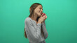 © Krakenimages.com - Woman holding red apple to cheek in studio with teal green background, eyes closed and gentle smile while embracing the fruit; contentment affection.