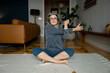 © Franci Leoncio - Senior woman stretching arms on rug at home