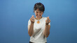 © Krakenimages.com - Young woman making pinched finger gesture with hands and multiple rings, wearing orange pendant and white tshirt in blue studio; playful.