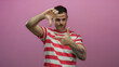© Krakenimages.com - Young man with tattoo in striped shirt posing against isolated pink background making hand frame gesture showcasing creative expression and style.