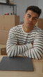 © Krakenimages.com - Young man relaxes in new home sitting at table in modern living room surrounded by packing boxes with laptop nearby suggesting a fresh start