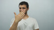 © Krakenimages.com - Young hispanic man hand covering mouth with puzzled frown and furrowed brow in pale blue studio; disgust.