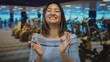 © Krakenimages.com - Woman clapping happily in a modern gym, with blue lighting reflecting on gym equipment, showcasing a cheerful atmosphere in a sports center.