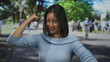 © Krakenimages.com - Young chinese woman smiling confidently on a bustling city street, raising her arm in a gesture of strength and empowerment, surrounded by a vibrant urban outdoor atmosphere.
