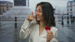 © Krakenimages.com - Woman smiling holding red heart paper while gesturing call me in a city outdoor setting with a blurred background of urban architecture.