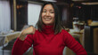 © Krakenimages.com - Woman smiling in restaurant pointing at herself wearing red sweater capturing joyful indoor moment in chinese coffee shop showcasing young energetic expression in cozy setting.