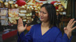 © Krakenimages.com - Woman gesturing in blue shirt in bustling market with colorful lights in urban street setting highlighting chinese cultural elements and lively market atmosphere.