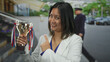 © Krakenimages.com - Young woman triumphantly holding trophy cup on city street showcasing success and achievement outdoors with smiling expression and modern urban backdrop.