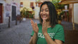 © Krakenimages.com - Young woman volunteer claps on a city street wearing a green t-shirt outside, capturing a cheerful and vibrant moment in an urban setting.