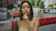 © Krakenimages.com - Woman at construction site outdoors gesturing silence with finger to lips amid equipment and barriers in an urban environment during daytime.