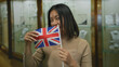 © Krakenimages.com - Young woman holding british flag smiling in jewelry store with showcase display