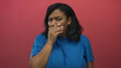 © Krakenimages.com - African american woman wearing blue t shirt covers mouth with hand in studio with red wall; disgust.