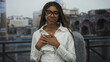© Krakenimages.com - Woman with hands on chest on a balcony at roman ruins building outdoors, wearing white shirt and glasses, smiling gently; gratitude sincerity.