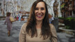 © Krakenimages.com - Woman smiling joyfully on a vibrant city street, her natural beauty and happiness reflecting a lively outdoor setting surrounded by blurred architectural details.