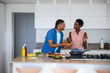 © wavebreak3 - Diverse friends cooking burger on kitchen island at home using wooden spatula and cutting board