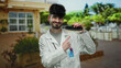 © Krakenimages.com - Young man in a white coat pointing at dental shade guide in an urban outdoor setting with blurred background of a city street.