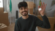 © Krakenimages.com - Young man smiling in new home surrounded by boxes holding house key in living room indicating successful moving and new beginnings