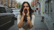 © Krakenimages.com - Woman cupping hands to mouth calling on a busy city street wearing white watch and braided bracelets, smiling with open mouth; joy announcement.