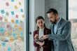 © Vladimir Borovic - Middle-Aged Man and Young Woman Focused Working in Modern Office with Sticky Notes – HR Concept