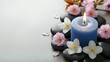 © Yuliia - Zen spa composition with blue candle, smooth stones and delicate pink flowers on neutral background for relaxation and wellness concepts.