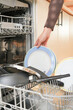 © AdriFerrer - A person is taking out a plate from a dishwasher