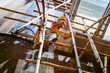 © Connect Images - Construction worker climbing bamboo scaffolding on a modern building site. Hongkong, China