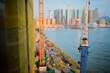 © Connect Images - Construction cranes and yellow tarp cover a building site beside a river with a cityscape backdrop. Hongkong, China
