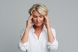 © Andrii Zastrozhnov - Mature caucasian woman with headache in white shirt against gray background