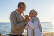 © Юлия Завалишина - Senior mature couple hugging enjoying outdoor recreation walking on beach. Old husband wife embracing with tenderness love enjoying sweet bonding. Grandmother grandfather together. Family moment love