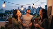© Ajronujen - Three friends laughing and enjoying drinks on balcony at night