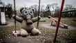 © Hidayat - Abandoned teddy bear wearing a gas mask sitting on a swing in a desolate playground, symbolizing lost childhood and the aftermath of war or nuclear fallout.
