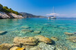 © RooM The Agency - Distant view of a sailboat anchored in the Ionian Sea by a beach, Ithaki, Greece