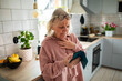 © Geber86 - Concerned senior woman reading smartphone in home kitchen