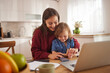 © Stockphotodirectors - A mother and her young child engage in a fun activity at the kitchen table, fostering connection and creativity together during a relaxed day at home.