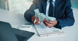 © WesJVR/peopleimages.com - Hands, person and calculate money in office for accounting, audit process and finance checklist. Accountant, cash and laptop with clipboard for tracking expenses, financial management and budgeting