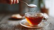 © Dao - Woman adding sugar into aromatic tea at wooden table indoors, closeup