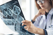 © tippapatt - Asian female orthopedics surgeon doctor examining patient's knee joint x-ray films, MRI bone, ct scan in radiology orthopedic unit in hospital. knee joint film x-ray, close up