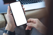 © tippapatt - Mockup blank screen cell phone, woman hands holding smartphone with empty screen for online marketing or mobile app design. Business woman using mobile phone and working on laptop at office, closeup
