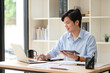 © matinee - Young businessman working at a desk with laptop and digital tablet in a bright modern office.