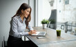 © matinee - Businesswoman focused on laptop work in a contemporary office with natural light.