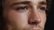 © Thares2020 - Close up of a young man s face with a tear glistening on his cheek conveying sadness and emotion