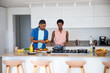 © wavebreak3 - Diverse couple cooking at countertop island in modern kitchen chopping vegetables on cutting board